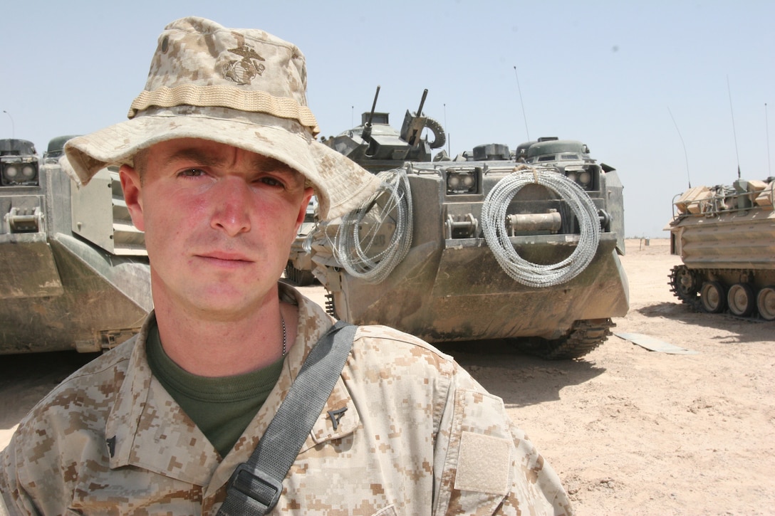 Lance Cpl. Daniel Rourk, crew chief, 3rd Platoon, Bravo Company, 2nd Assault Amphibian Battalion, 2nd Marine Division, stands in front of a row of amphibious assault vehicles May 22. Rourk, who is on his first deployment to Iraq, is trained in Arabic and serves as a translator for Bravo Company.