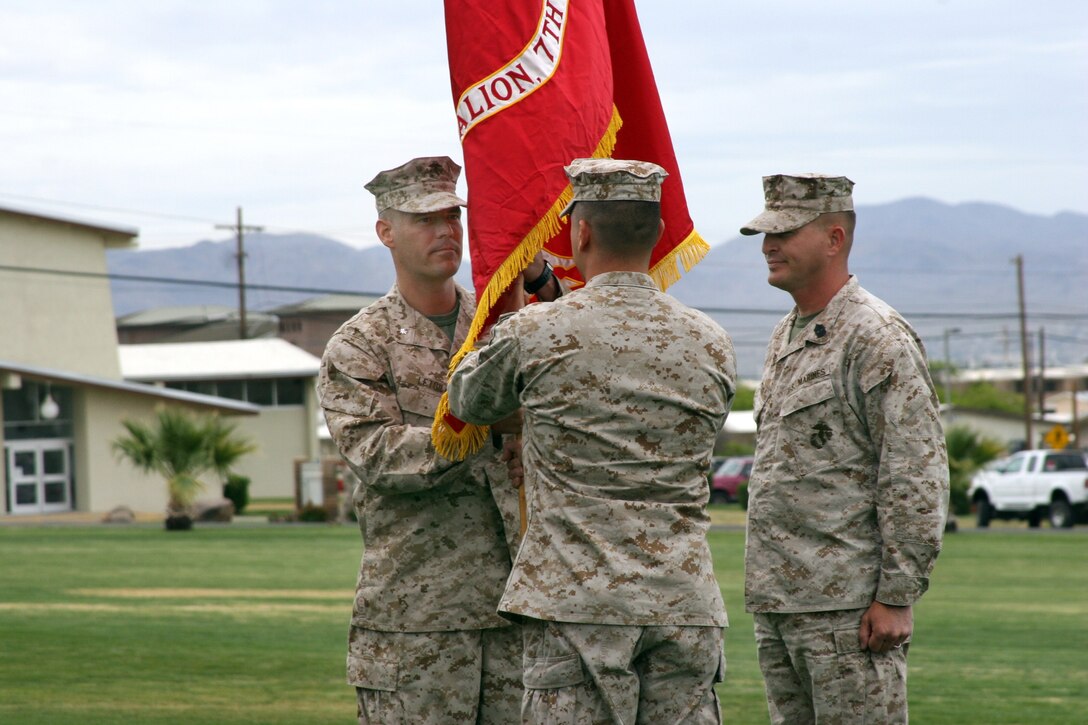 With 2nd Battalion, 7th Marines sergeant major, Sgt. Maj. David L. Plaster standing by, Lt. Col. Philip C. Skuta, battalion commanding officer, passes the battalion battle colors to his successor, Lt. Col. Joseph A. L'Etoile April 22 on the Commanding General's Parade Deck.  This symbolic exchange represents the transfer of power from outgoing to incoming commander in front of the formation of Marines under the command.
