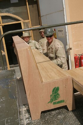 Petty Officer 1st class William White, builder, and Petty Officer 2nd class Chris Roberts, steel worker, load a bench Seabees built for the Post Exchange barber shop March 23. The Sailors of Naval Mobile Construction Battalion 24 took over the mission in a small ceremony earlier that day.