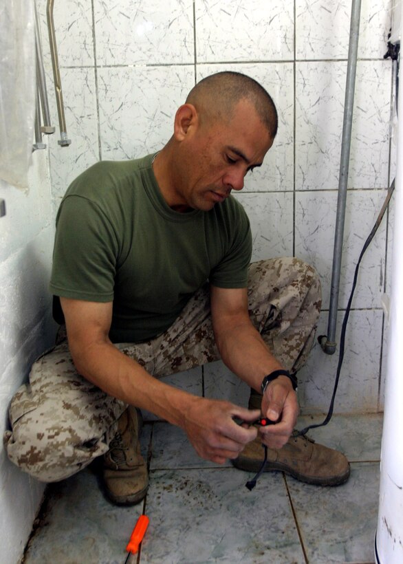 HADITHAH, Al Anbar, Iraq- 38 year old  San Antonio native Gunnery Sgt. Joe A. Sepulveda,an motor transportation operation chief with 3/25, begins work on a broken water heater at the dam. (Official USMC Photo by Corporal Ken Melton)
