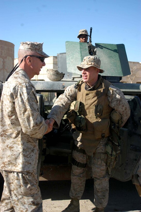 CAMP HURRICANE POINT Ar Ramadi, Iraq (April 6, 2005) - Corporal Tyler S. Trovillion, a grenadier and team leader with 3rd Squad, 2nd Platoon, Company A, 1st Battalion, 5th Marine Regiment, had the pleasure of meeting General Michael ? Haggee, Commandant of the Marine Corps, here April 6. Lance Cpl. Dion M. Whitley, a machine gunner in Trovillion's squad, looks on while positioned in the turret of a Humvee. Trovillion, 23, of Richardson, Texas, and Whitley, 21, of Pasadena, Calif., and three of their 3rd Squad comrades were killed June 15 when an improvised explosive device detonated underneath their Humvee. A Navy Corpsman with the infantry battalion died the same day in a different incident. The brave warriors were honored with a memorial ceremony at Camp Hurricane Point June 23. Photo by: Cpl. Tom Sloan