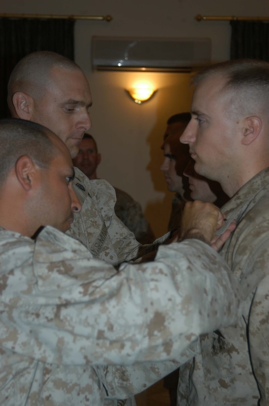 CAMP HURRICANE POINT Ar Ramadi, Iraq (May 23, 2005) - Gunnery Sgt. John B. Kelsch, and Staff Sgt. Ray A. Valdez, both with 4th Platoon, Company A, 1st Combat Engineer Battalion, which is in direct support of 1st Battalion, 5th Marine Regiment, pin first lieutenant rank insignia on the collar of their commander, Douglas R. Orr, during his promotion ceremony here. The 23-year-old from Ridgefield, Conn., transitioned from gold to silver along with three other Marine officers with 1st Battalion, 5th Marines. Orr graduated from the United States Navel Academy Annapolis, Md., and holds a Bachelors of Science degree in political science. Photo by: Cpl. Tom Sloan