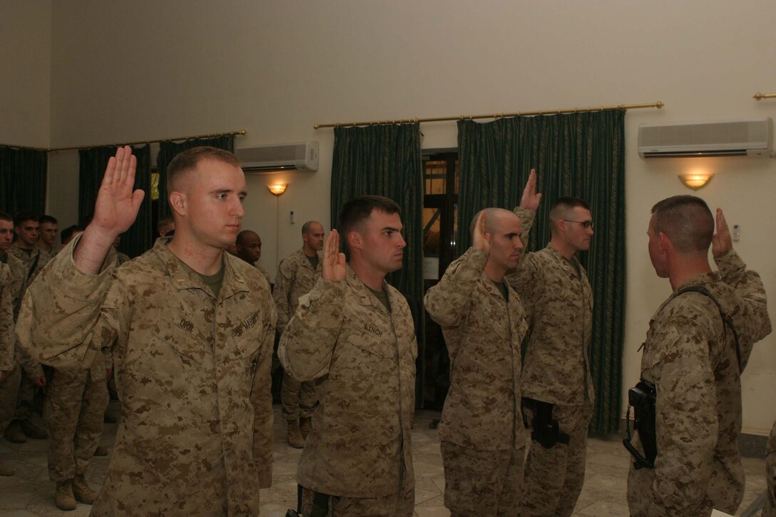 CAMP HURRICANE POINT Ar Ramadi, Iraq (May 23, 2005) - With their right hands raised, second lieutenants Douglas R. Orr, Declan J. Lynch, Adam W. Burch and Eldon W. Beck, who're all with 1st Battalion, 5th Marine Regiment, take their oath of office from the infantry battalion's commander, Lt. Col. Eric M. Smith, during a promotion ceremony here. The four Marine leaders pinned on the rank of first lieutenant. More than 40 comrades attended the event to honor the first lieutenants on their day of advancement. Photo by: Cpl. Tom Sloan