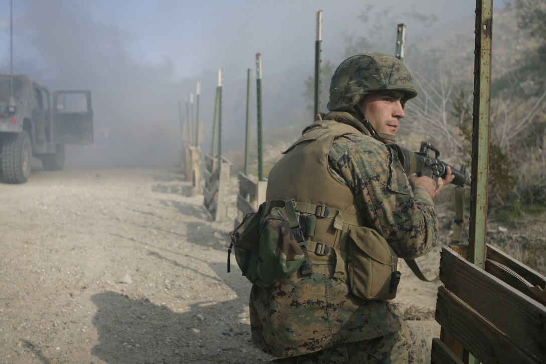 MARINE CORPS AIR-GROUND COMBAT CENTER TWENTYNINE PALMS, Calif. - Lance Cpl. Simon A. Fry, motor transport operator with 1st Battalion, 6th Marine Regiment, takes a knee and prepares to aim his rifle shortly after his convoy came under attack during a convoy operations course here.  The unit conducted a Revised Combined Arms Exercise to prepare for a deployment to Iraq in March.