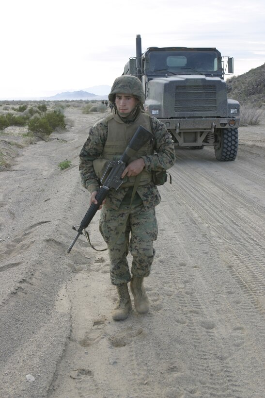 MARINE CORPS AIR-GROUND COMBAT CENTER TWENTYNINE PALMS, Calif. - Lance Cpl. Simon A. Fry, motor transport operator with 1st Battalion, 6th Marine Regiment, patrols in front of his seven-ton truck as his convoy prepares to enter a mock Iraqi village here.  The unit conducted a Revised Combined Arms Exercise to prepare for deployment to Iraq in March.