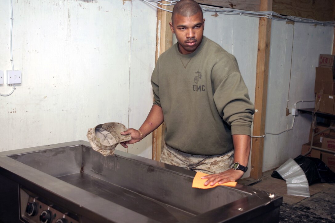 CAMP BAHARIA, Iraq - Lance Cpl. Jarmon C. Ward, 1st Battalion, 6th Marine Regiment cook, wipes down the unit's field mess equipment after the morning meal.  Ward and fellow cooks work approximately 18 hours every day to ensure all the unit's Marines are well fed.