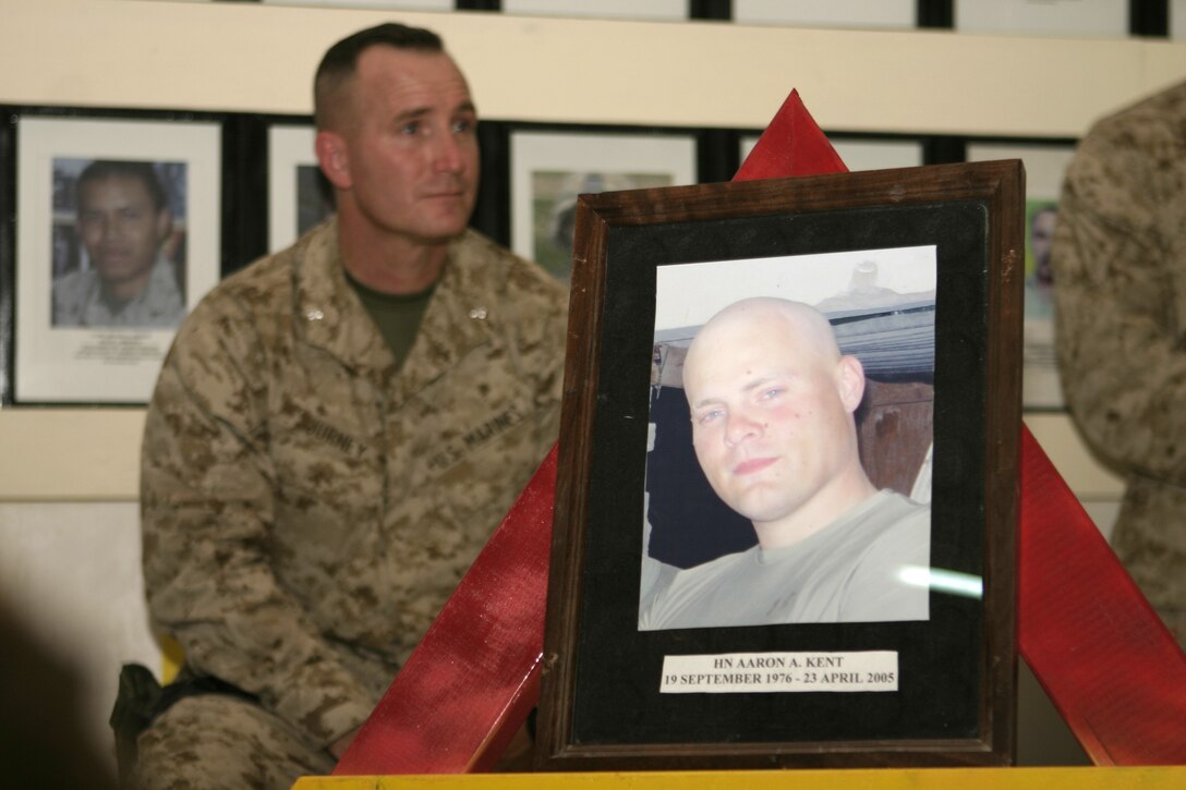CAMP BAHARIA, Iraq - Hospitalman Aaron A. Kent's photo rests atop a stand inside the Baharia chapel during a memorial service here April 24, as Lt. Col. William M. Jurney, 1st Battalion, 6th Marine Regiment's commander, looks on in the background.  The 28-year-old Portland, Ore. native passed away April 23 when his vehicle struck an improvised explosive device in a roadway outside Fallujah.