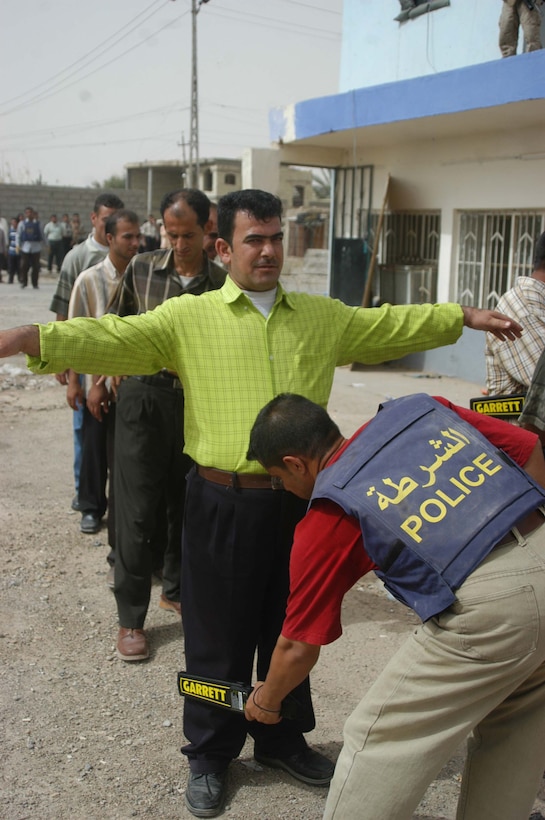 AR RAMADI, Iraq (May 24, 2005) - An Iraqi Police Officer searches a man at the Ramadi Police Headquarters here. The man volunteered to be an Iraqi Police Officer and must undergo screening by 1st Battalion, 5th Marine Regiment, at their facility inside the police headquarters before being issued a sidearm, badge and paid a salary. The infantry battalion is conducting an operation to ensure qualified men fill the forces' ranks.The men take a written and oral exam, are given a physical examination, are entered into the infantry battalion's biometric automated toolset and are questioned as to why they want to serve. More than 500 Iraqis have volunteered. Photo by: Cpl. Tom Sloan