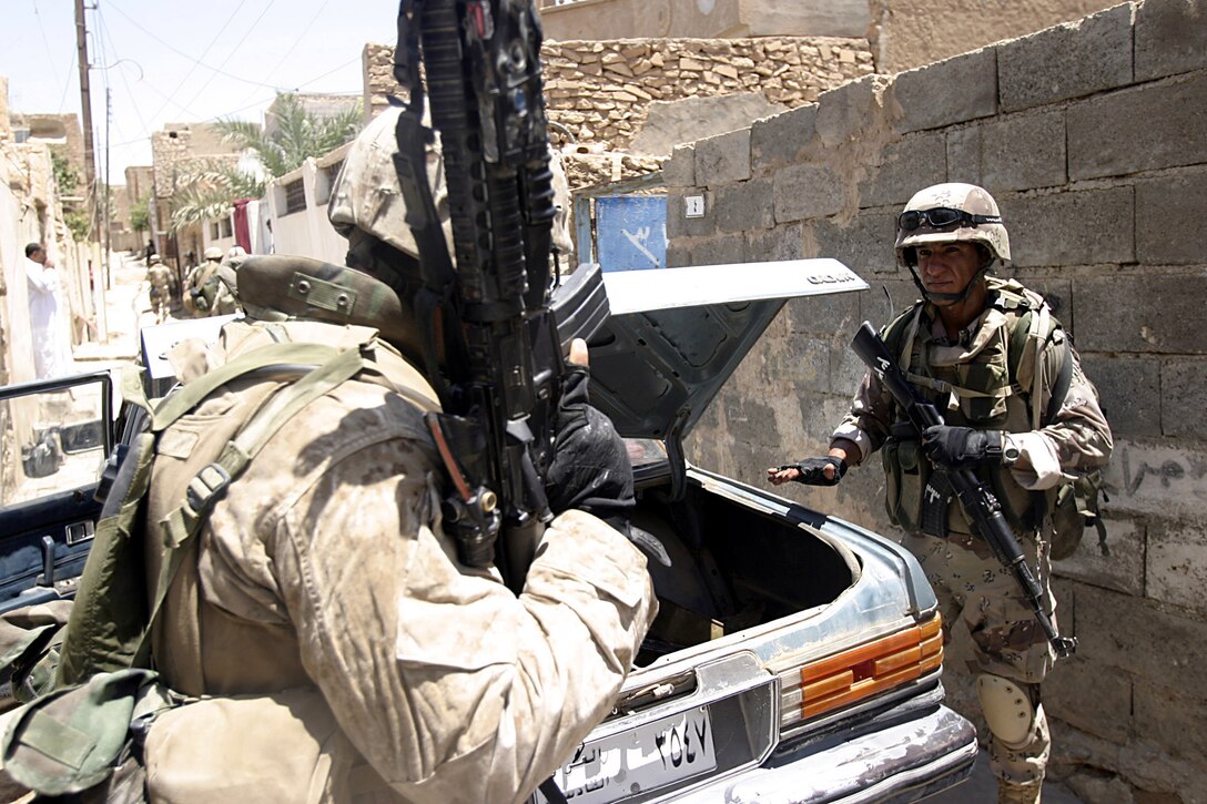 Hit, Al Anbar, Iraq (July 22, 2005)--A Marine with Company "K", 3rd Battalion, 25th Marine Regiment and a soldier with Iraq Intervention Force check out a suspicious vehicle while on patrol. (Official USMC Photo by Corporal Ken Melton)