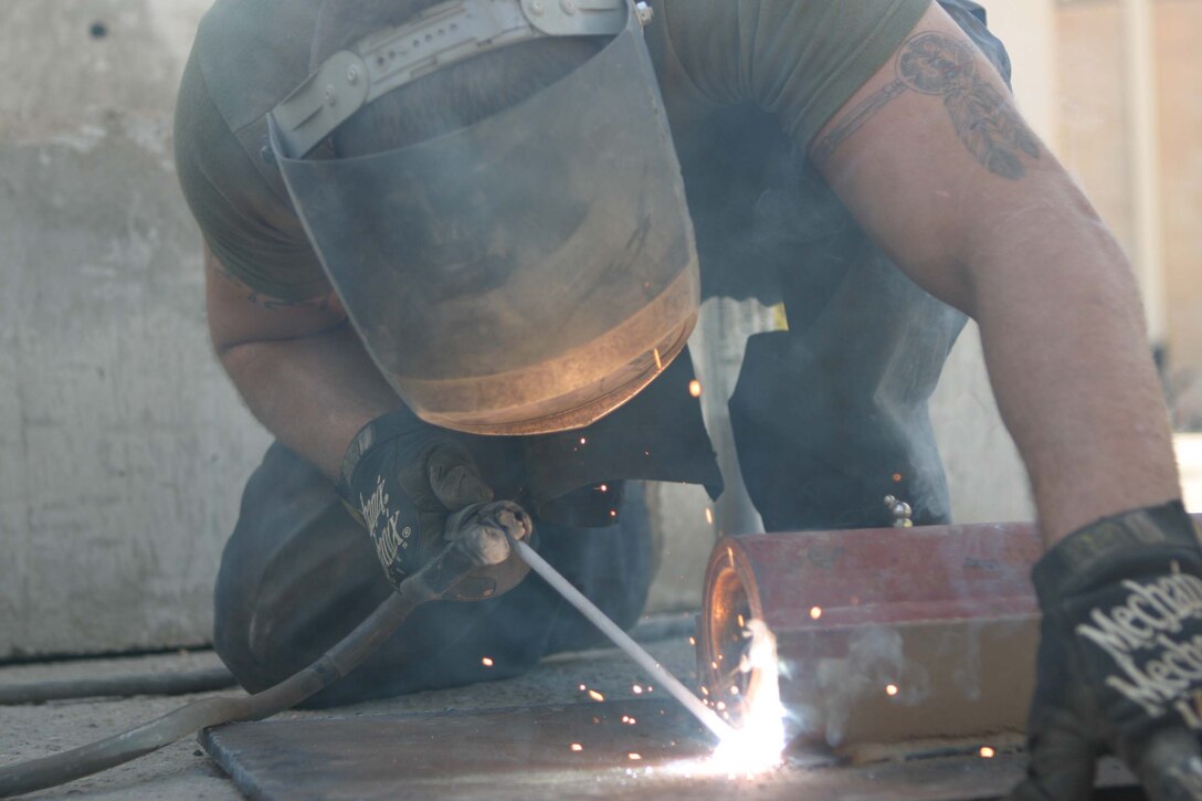 CAMP BLUE DIAMOND, RAMADI, Iraq - Lance Cpl. Anthony S. Loftin a motor transport mechanic with Truck Company, Headquarters Battalion, 2nd Marine Division  welds a metal hinge for a gate that will be used to help lead Iraqi citizens into the Al Anbar Government Center to vote in Iraq's elections this October. Loftin has used the welding skills he learned while working at his grandfathers automotive shop in Arkansas to fabricate the numerous guard towers, rolling gates and other metal structures on the camp. Official Marine Corps photo by: Sgt Ryan S. Scranton