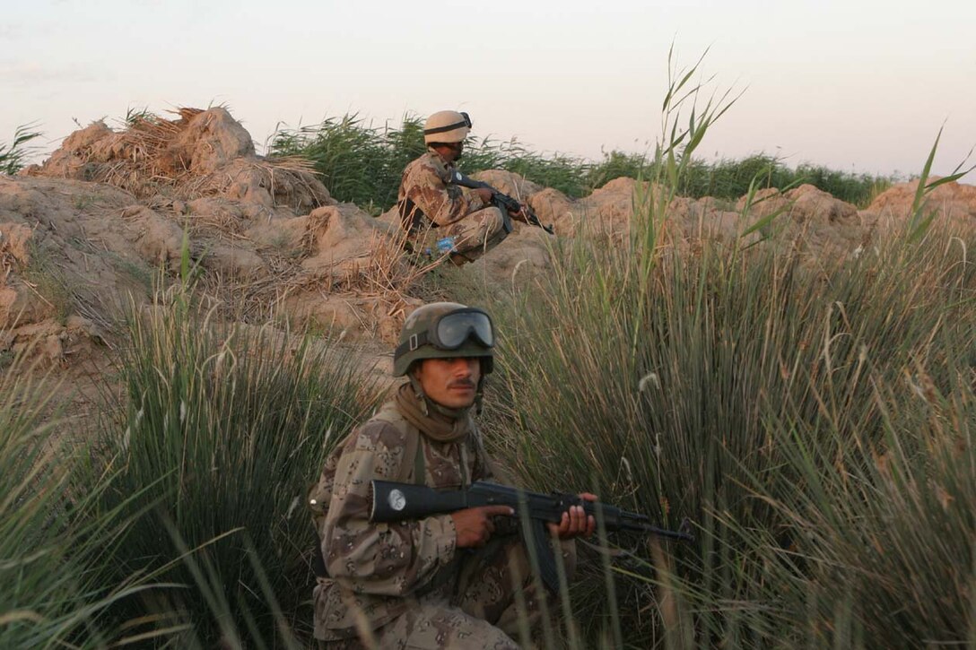 AL KARMAH, IRAQ -- Iraqi Security Force members sit in the shrubery waiting for oncoming traffic to stop and check for illegal weapons systems or any type of improvised explosive devices.  The ISF have watched and learned from the Marines over the past four months on how to effectively check vehicles and personnel.  Official U.S. Marine Corps photo by Lance Cpl. Athanasios L. Genos