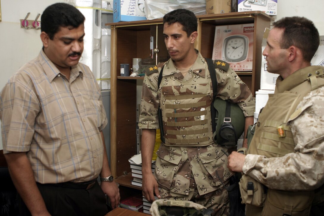 FALLUJAH, Iraq - An Iraqi doctor speaks with a local physician and Navy Lt. Jared Vogler, 1st Battalion, 6th Marine Regiment medical officer, inside a clinic here Aug. 25 during Operation Medical Mentoring.  U.S. Marines and Iraqi Security Forces visited several local clinics to hand out supplies such as children's cough suppressants, blood pressure regulating medications, and as many as 100,000 Tylenol tablets.