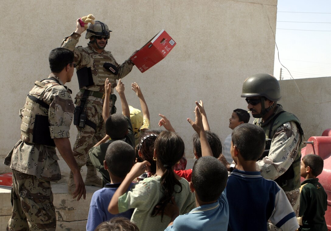 FALLUJAH, Iraq - An Iraqi soldier hands children stuffed animals outside a clinic here Aug. 25 during Operation Medical Mentoring.  U.S. Marines and Iraqi Security Forces visited several local clinics to hand out supplies such as children's cough suppressants, blood pressure regulating medications, and as many as 100,000 Tylenol tablets.