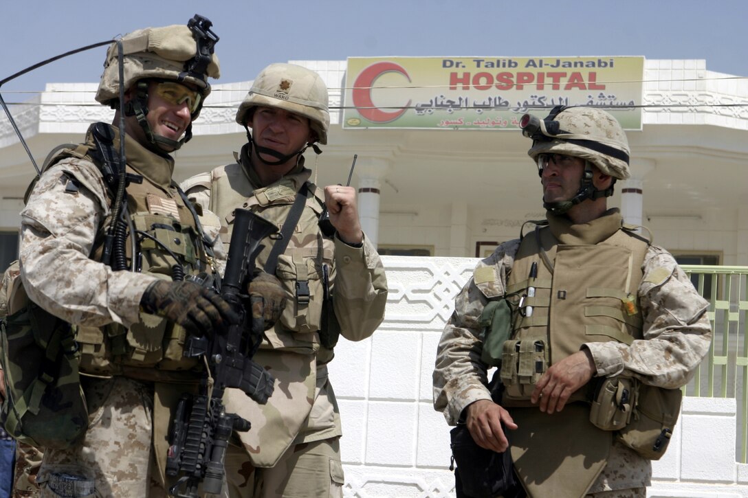 FALLUJAH, Iraq - From left to right: 1st Lt. Thomas Waller, Company B's, 1st Battalion, 6th Marine Regiment executive officer; a soldier; and Navy Lt. Jared Vogler, 1st Battalion, 6th Marine Regiment's medical officer; speak outside a hospital here Aug. 25 during Operation Medical Mentoring.  U.S. Marines and Iraqi Security Forces visited several local clinics to hand out supplies such as children's cough suppressants, blood pressure regulating medications, and as many as 100,000 Tylenol tablets.