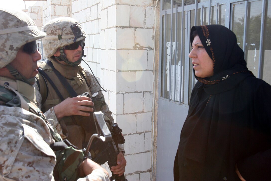 AR RAMADI, Iraq (September 25, 2005) - Gunnery Sgt. John Satanek, team chief for CAG team 4, speaks with the vice principal of local school through an interpreter during an information operations/civil affairs group patrol Sept. 25. The patrol stopped by the school to see if the school needed any textbooks or supplies. Photo by Cpl. Shane Suzuki