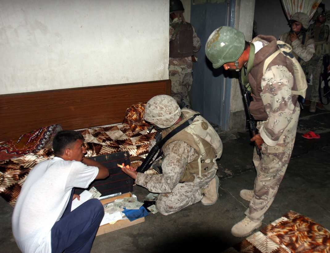AR RAMADI, Iraq (September 25, 2005) -- A Marine from Company L, 3rd Battalion, 7th Marine Regiment and a member of the local Iraqi Security Force work together to go through documents during a raid to capture three men suspected of attacking Marine forces working the area. The raid ended with the capture of three suspects. Photo by Cpl. Shane Suzuki.