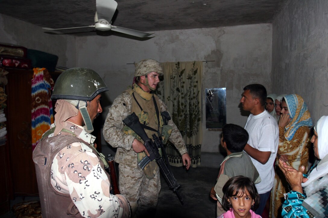 AR RAMADI, Iraq (September 25, 2005) - A Marine from Company L, 3rd Battalion, 7th Marine Regiment and a member of the local Iraqi Security Force work together to questions a family about recent insurgent activities during a raid Sept. 25. The raid ended with the capture of three suspects. Photo by Cpl. Shane Suzuki.