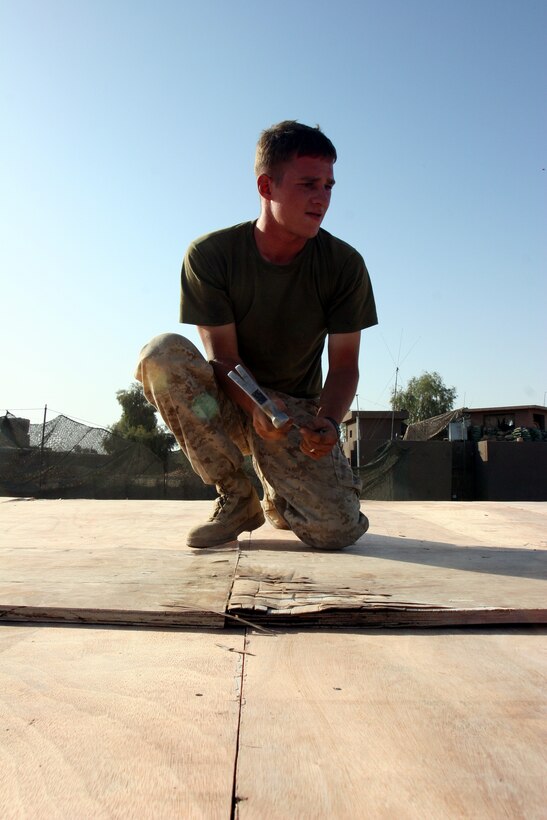 AR RAMADI, Iraq (September 25, 2005) - Corporal Joseph Holloway, a combat engineer from 1st Combat Engineer Battalion, works to nail down a piece of the roof on a new living space for visiting members of the Iraqi Security Forces at Snake Pit Sept. 25. Photo by Cpl. Shane Suzuki.