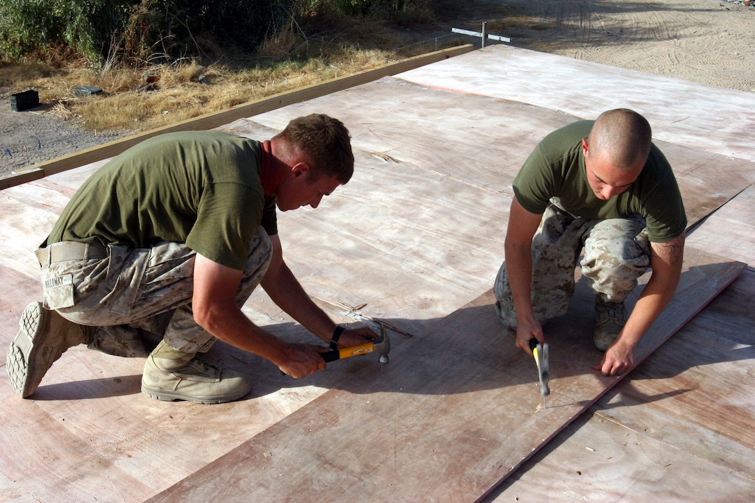 AR RAMADI, Iraq (September 25, 2005) - Corporal Joseph Holloway, a combat engineer from 1st Combat Engineer Battalion, and Lance Cpl. Jason Smither, a infantryman from Weapons Platoon, Company L, work together to nail down a piece of the roof on a new living space for visiting members of the Iraqi Security Forces at Snake Pit Sept. 25. Photo by Cpl. Shane Suzuki.