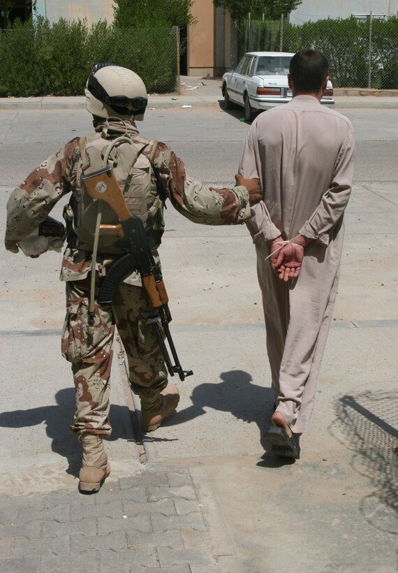 An Iraqi soldier attached to Iraqi Army Platoon, Echo Company, 3rd Reconnaissance Battalion, 2nd Marine Division, takes away a suspected insurgent during Operation Southern Fire late August in Ferris Town. The main objective for the platoon was setting up voting polls for Iraq?s referendum vote held October 15.