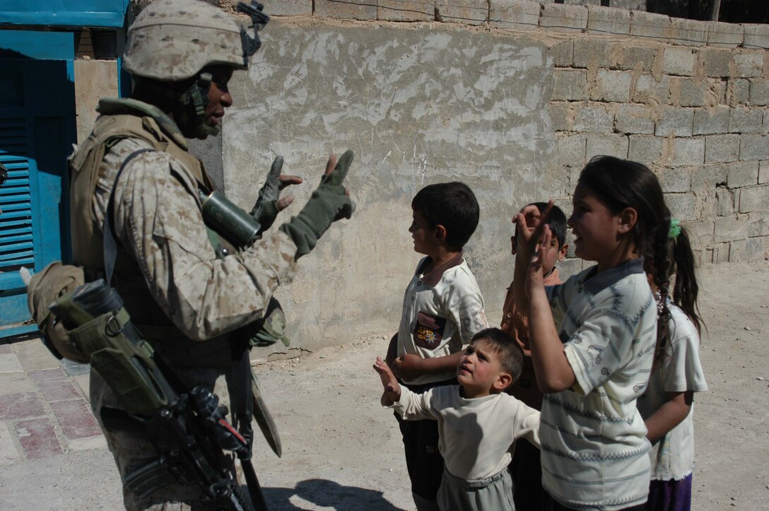 AR RAMADI, Iraq (March 25, 2005) - Sergeant Willie E. Brown, squad leader, 2nd Squad, 1st Platoon, Company B, 1st Battalion, 5th Marines, shows some Iraqi children how to count in English using their fingers. Leathernecks with 1st Platoon, Company B, 1st Battalion, 5th Marines, searched several houses in the western part of the city here March 25 for a man they suspect is a member of the jihad group Jaysh Mohamed, which is connected with producing improvised explosive devises and has been linked to several IED attacks. They also searched for illegal weapons, weapons caches and checked identification cards of the men in each house they searched. The Marines were accepted well by the people they searched and by the children who gathered around them in the streets. The Marines gave out soccer balls, pens and paper, sunglasses and candy to the children. Photo by Cpl. Tom Sloan