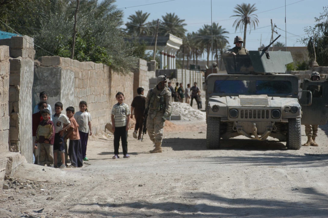 AR RAMADI, Iraq (March 25, 2005) - Scores of Iraqi children gathered around the Marines posting security in the streets. The children greeted them grinning from ear to ear eager to show off to their Marine visitors by speaking to them what English words they knew. Leathernecks with 1st Platoon, Company B, 1st Battalion, 5th Marines, searched several houses in the western part of the city here March 25 for a man they suspect is a member of the jihad group Jaysh Mohamed, which is connected with producing improvised explosive devises and has been linked to several IED attacks. They also searched for illegal weapons, weapons caches and checked identification cards of the men in each house they searched. The Marines were accepted well by the people they searched and by the children who gathered around them in the streets. The Marines gave out soccer balls, pens and paper, sunglasses and candy to the children. Photo by Cpl. Tom Sloan