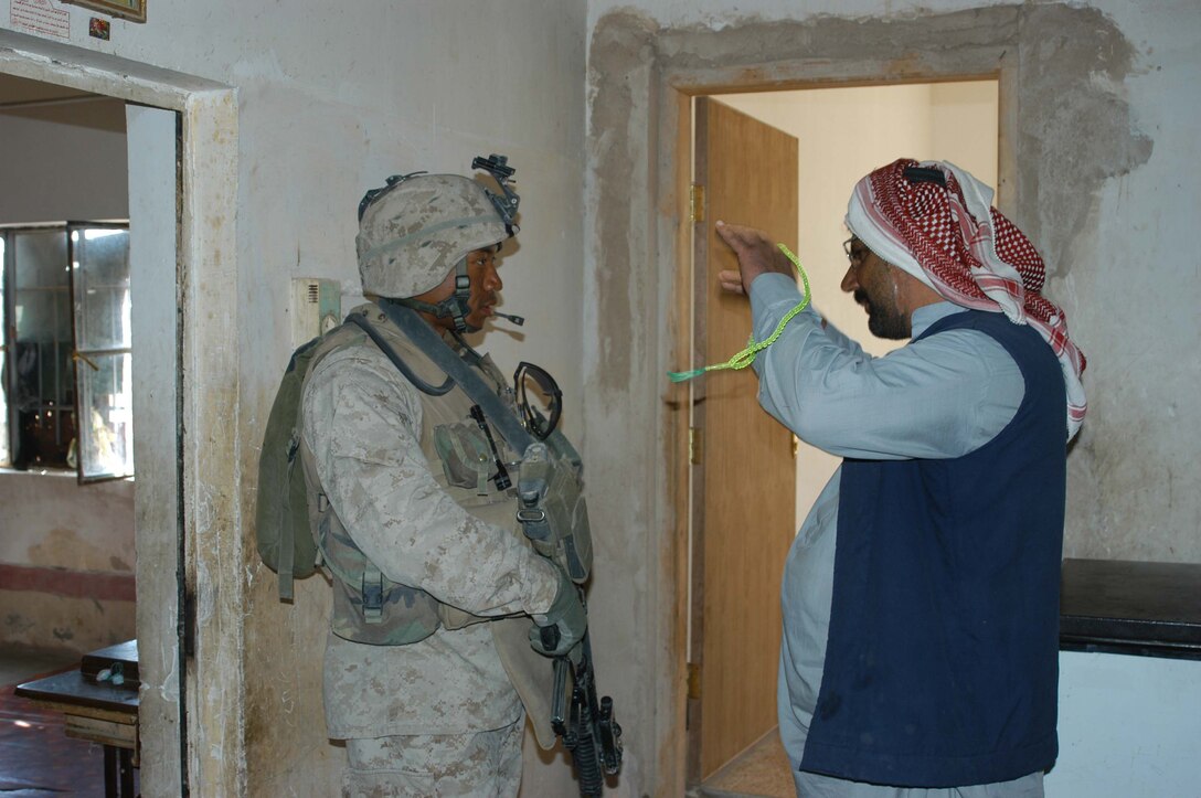 AR RAMADI, Iraq (March 25, 2005) - Lance Cpl. Marzette A. Henderson, 28, of Long Beach, Calif., and team leader for 2nd Squad, 1st Platoon, Company B, 1st Battalion, 5th Marines, listen to an Iraqi man explain that he doesn't know who he and his Marines are looking for. Leathernecks with 1st Platoon, Company B, 1st Battalion, 5th Marines, searched several houses in the western part of the city here March 25 for a man they suspect is a member of the jihad group Jaysh Mohamed, which is connected with producing improvised explosive devises and has been linked to several IED attacks. They also searched for illegal weapons, weapons caches and checked identification cards of the men in each house they searched. The Marines were accepted well by the people they searched and by the children who gathered around them in the streets. The Marines gave out soccer balls, pens and paper, sunglasses and candy to the children. Photo by Cpl. Tom Sloan