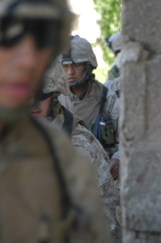 AR RAMADI, Iraq (March 25, 2005) - A squad of Marines round the corner of a building they're about to search. Leathernecks with 1st Platoon, Company B, 1st Battalion, 5th Marines, searched several houses in the western part of the city here March 25 for a man they suspect is a member of the jihad group Jaysh Mohamed, which is connected with producing improvised explosive devises and has been linked to several IED attacks. They also searched for illegal weapons, weapons caches and checked identification cards of the men in each house they searched. The Marines were accepted well by the people they searched and by the children who gathered around them in the streets. The Marines gave out soccer balls, pens and paper, sunglasses and candy to the children. Photo by Cpl. Tom Sloan