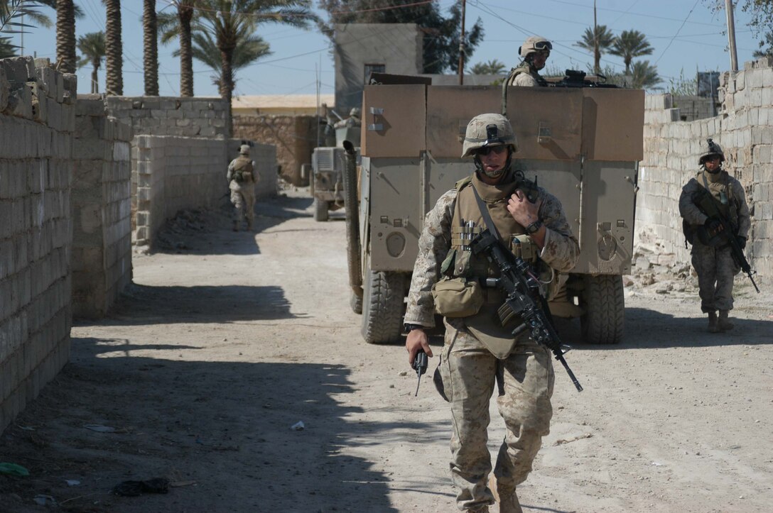 AR RAMADI, Iraq (March 25, 2005) -Twenty-four-year-old 1st Lt. Cole M. Clements, platoon commander, 1st Platoon, Company B, 1st Battalion, 5th Marines, of Douglasville, Texas tells his Marines on his radio to search the next sector of houses. Leathernecks with 1st Platoon, Company B, 1st Battalion, 5th Marines, searched several houses in the western part of the city here March 25 for a man they suspect is a member of the jihad group Jaysh Mohamed, which is connected with producing improvised explosive devises and has been linked to several IED attacks. They also searched for illegal weapons, weapons caches and checked identification cards of the men in each house they searched. The Marines were accepted well by the people they searched and by the children who gathered around them in the streets. The Marines gave out soccer balls, pens and paper, sunglasses and candy to the children. Photo by Cpl. Tom Sloan