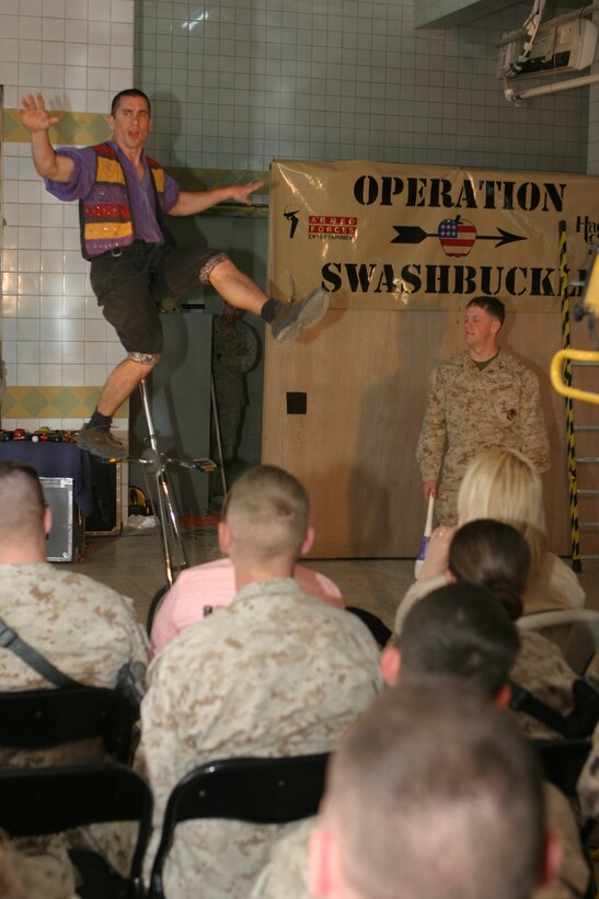 CAMP BLUE DIAMOND, AR RAMADI, Iraq - Juggler, comedian and award-winning motivational speaker, Dan Thurmon, demonstrates his skill on a unicycle during Operation Swashbuckle. Thurmon is a member of the four-man comedy show presented by Hack and Slash, who provided an explosive round of entertainment for more than 100 Marines, sailors and soldiers here serving with the 2nd Marine Division in support of Operation Iraqi Freedom.