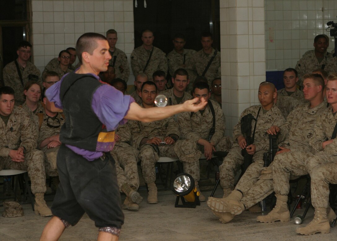 CAMP BLUE DIAMOND, AR RAMADI, Iraq - Service members look on as Juggler, comedian and award-winning motivational speaker, Dan Thurmon, demonstrates his juggling skill rolling first one then up to five crystal balls over his body at one time during Operation Swashbuckle. Thurmon is a member of the four-man comedy show presented by Hack and Slash, who provided an explosive round of entertainment for more than 100 Marines, sailors and soldiers here serving with the 2nd Marine Division in support of Operation Iraqi Freedom.