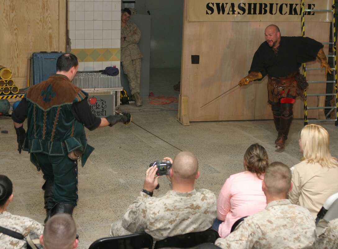 CAMP BLUE DIAMOND, AR RAMADI, Iraq - The Hack and Slash 'Shakespearean comic-sword fighting duo,' John Davis (right) and Spencer Humm (left) duel over who will lay on the bed of 1,000 spikes during Operation Swashbuckle. Hack and Slash presented the four-man comedy show that provided an explosive round of entertainment for more than 100 Marines, sailors and soldiers here serving with the 2nd Marine Division in support of Operation Iraqi Freedom.
