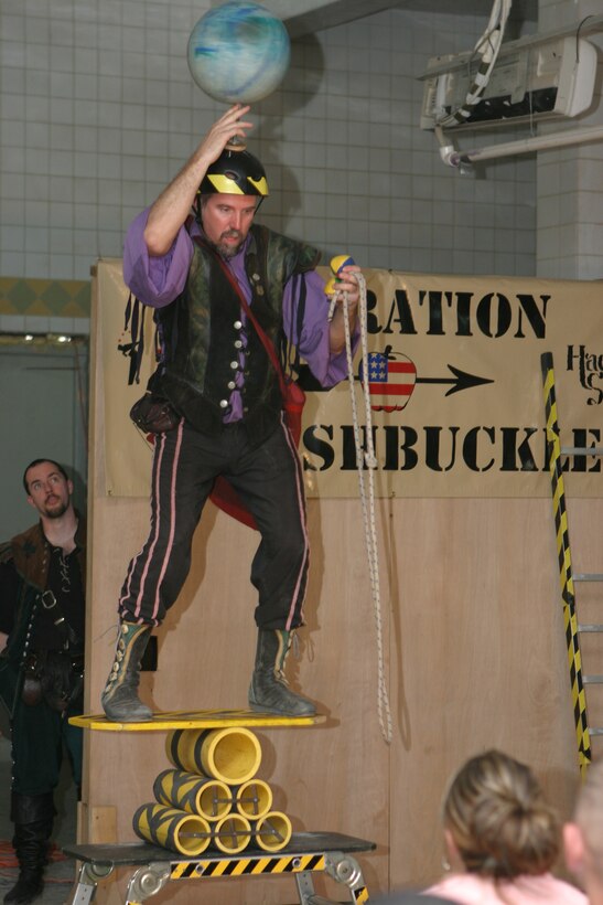 Juggler, comedian and trickster, Todd Key of Grantville, Ga., gets a ball spinning on his spiked helmet while balancing on a stack of tubes and preparing to juggle a couple of balls with one hand and twirl a lasso with the other during Operation Swashbuckle. The 42-year-old Keys is part of a four-man comedy show presented by Hack and Slash, who provided an explosive round of entertainment for more than 100 Marines, sailors and soldiers here serving with the 2nd Marine Division in support of Operation Iraqi Freedom.