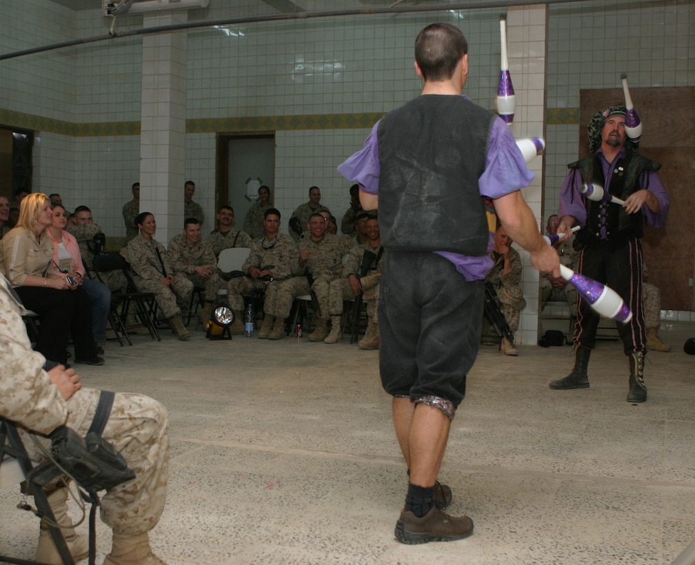 CAMP BLUE DIAMOND, AR RAMADI, Iraq - Service members watch as comedic juggling team, Todd Key (right) and Dan Thurmon (left) spin six pins through the air between them during Operation Swashbuckle. The jugglers a part of a four-man comedy show presented by Hack and Slash, who provided an explosive round of entertainment for more than 100 Marines, sailors and soldiers here serving with the 2nd Marine Division in support of Operation Iraqi Freedom.