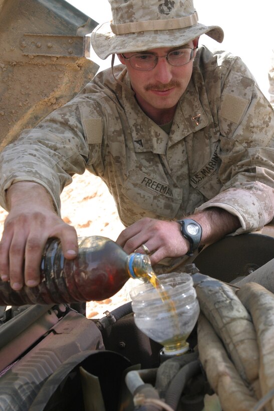 CAMP KOREAN VILLAGE, Iraq -- Lance Corporal Damion Freeman, a 23-year-old Kansas City, Mo. native and military policeman with 2nd Military Police Battalion, 4th Tank Battalion, pours oil into his High Mobility Multi-Wheeled Vehicle before a convoy, March 26.  Freeman is a 1999 Shawnee Mission Northwest High School graduate and reservist. U.S. Marine Corps photo by Sgt. Stephen D'Alessio (RELEASED)
