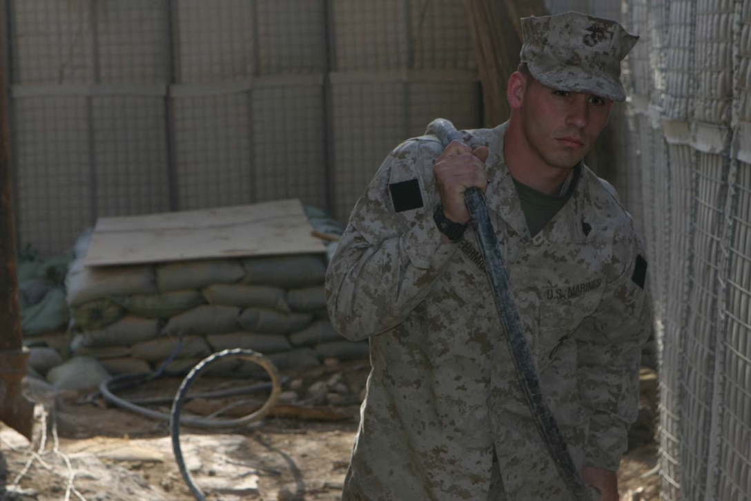 CAMP FALLUJAH, IRAQ - Laying wire around the command operations center, Sgt. James Behrmann, Assistant Field Wireman Chief, ensures communications are up and going everyday.  Making sure the wires are laid correctly and working on the switchboard are Behrmann's daily tasks.  Official U.S. Marine Corps photo by Lance Cpl. Athanasios L. Genos.