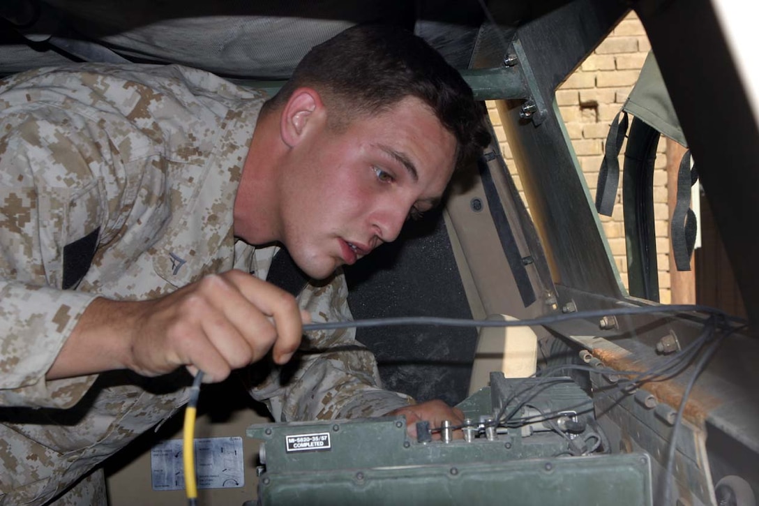 CAMP FALLUJAH, IRAQ - Working on what the Marines call "Zeus," Lance Cpl. John R. Camisa, radio technician, and Spring Hill, Fla., native, works on troubleshooting recent problems with the wiring in the vehicle.  Camisa and his fellow Marines work daily fixing any and all radio problems in vehicles and command operation centers for the battalion and company levels.  Official U.S. Marine Corps photo by Lance Cpl. Athanasios L. Genos.