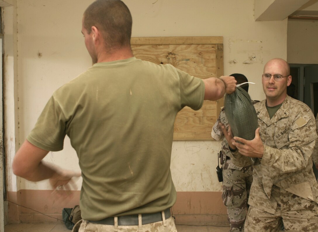 SAQLAWIYAH, Iraq - When not offering worship services or speaking with Marines and sailors, Navy Lt. Richard Ryan, 1st Battalion, 6th Marine Regiment's chaplain, still enjoys helping out his troops.  The 30-year-old Hendersonville, Tenn. native helps Marines with Company A, 1st Battalion, 6th Marine Regiment fortify their base of operations here April 19 by helping them carry sandbags used to build makeshift bunkers.