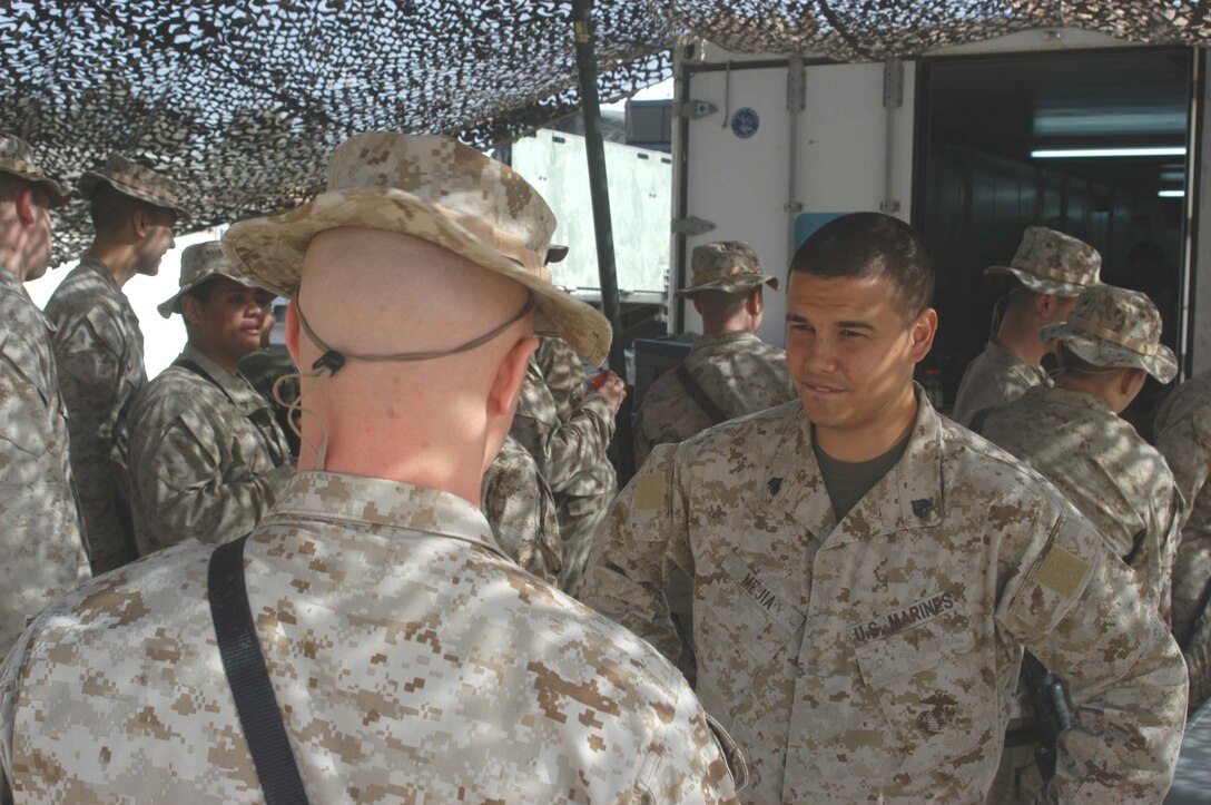 CAMP HURRICANE POINT, Ar Ramadi, Iraq (April 21, 2005) -Sergeant Miguel E. Mejia, retail store manager with Headquarters and Service Company, 2nd Force Service Support Group, 2nd Marine Division, talks to a customer outside the post exchange here. The 24-year-old Salinas, Puerto Rico native, runs the Warfighter Express Service Team, which provides exchange items for purchase, dispersing and postal services to warriors fighting on the frontlines of the urban battlefield. Each week, Mejia loads a 7-ton truck full of merchandise from the Camp Ramadi Exchange and visits Camps Snake Pit and HP where Marines with 1st Battalion, 5th Marines reside. Photo by Cpl. Tom Sloan