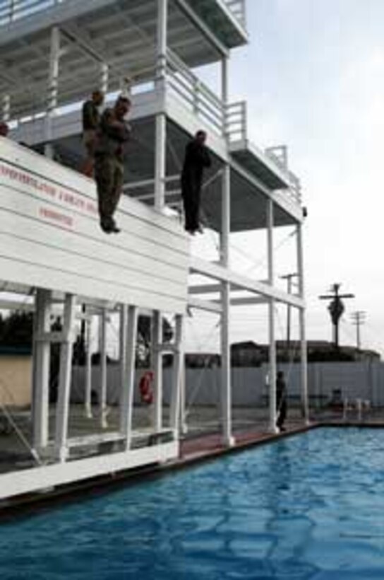 Two Marines jump off the three meter tower while conducting their fourth class swim qualification at the 43 Area Swim Tank. More than 40 Marines from the 15th Marine Expeditionary Unit completed their swim qualifications in preparation for their upcoming deployment next year.