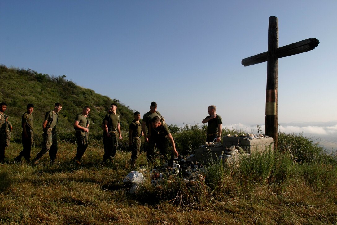 Marines from 1st Battalion, 4th Marine Regiment, place white stones at the base of a memorial site for Marines from 1st Marines that died during Operation Iraqi Freedom I and II outside of Camp Horno, April 26. Every Marine that hikes up San Onofre Mountain to the memorial carries a white stone to place at the memorial's base.