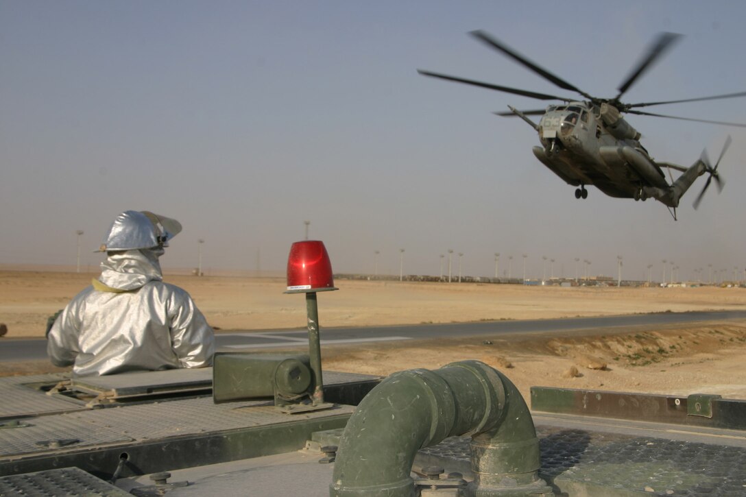 Corporal Gregory Hollins, rescueman, Aircraft, Rescue and Firefighting watches closely as a CH-53 Super Stallion lands aboard forward armed refueling point Al Qaim, Iraq, March 27. Hollins is one of four crash crewmen who are responsible for all aircraft and structural fire defense in Al Qaim.