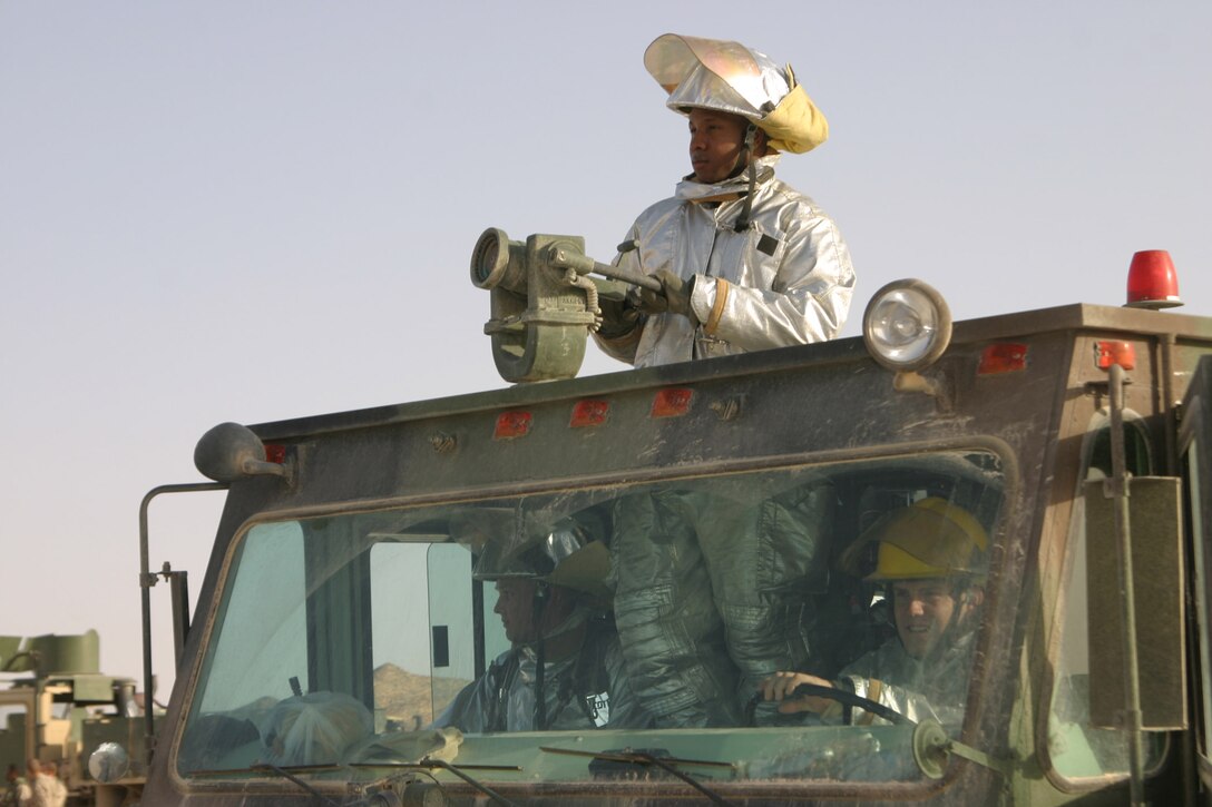 Corporal Gregory Hollins, Sgt. Robert Tidquist and Lance Cpl. Ben Schrock, crash crewmen, Aircraft, Rescue and Firefighting make sure there are no problems while a CH-53 Super Stallion lands aboard forward armed refueling point Al Qaim, Iraq. ARFF has four Marines in Al Qaim who are responsible for all aircraft and structural fire defense.