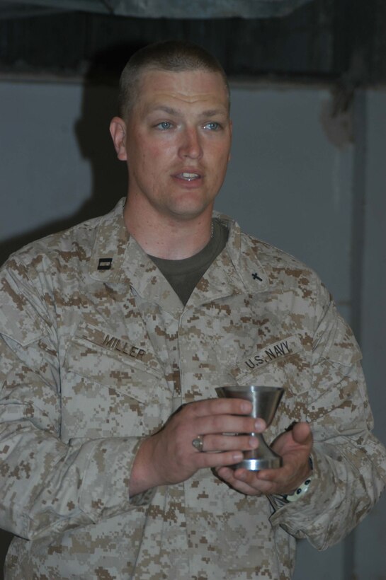 AR RAMADI, Iraq (March 27, 2005) - Navy Lt. Aaron T. Miller, chaplain for 1st Battalion, 5th Marine Regiment, offers Holly Communion to Marines while conducting Easter service at observation post VA here. The 32-year-old man of God from Redlands, Calif., visited Marines from the infantry battalion's five companies of whom he preached a hasty Easter service and served Holy Communion to. The effort, which lasted more than six hours, required Miller to travel to seven different places in the city where Marines are serving. Photo by Cpl. Tom Sloan