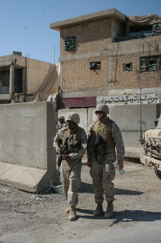 AR RAMADI, Iraq (March 27, 2005) - Twenty-two-year-old Birmingham, Ala., native Petty Officer 3rd Class Ternandez M. Calloway, religious program specialist, with his rifle at the ready, keeps his eyes peeled for threats while escorting Navy Lt. Aaron T. Miller, chaplain for 1st Battalion, 5th Marine Regiment, from observation post 295 here. The 32-year-old man of God from Redlands, Calif., visited Marines from the infantry battalion's five companies of whom he preached a hasty Easter service and served Holy Communion to. The effort, which lasted more than six hours, required Miller to travel to seven different places in the city where Marines are serving. Photo by Cpl. Tom Sloan
