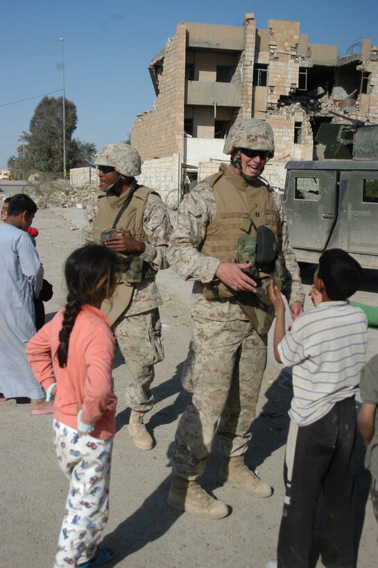 AR RAMADI, Iraq (March 27, 2005) - Navy Lt. Aaron T. Miller,(right) chaplain for 1st Battalion, 5th Marine Regiment, and his religious program specialist, 22-year-old Petty Officer 3rd Class Ternandez M. Calloway of Birmingham, Ala., greet Iraqi children outside observation post Ghetto here. The 32-year-old man of God from Redlands, Calif., visited Marines from the infantry battalion's five companies of whom he preached a hasty Easter service and served Holy Communion to. The effort, which lasted more than six hours, required Miller to travel to seven different places in the city where Marines are serving. Photo by Cpl. Tom Sloan