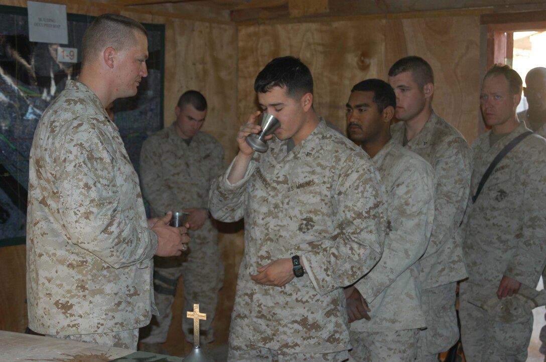 AR RAMADI, Iraq (March 27, 2005) -Twenty-year-old Lance Cpl. Gerardo Hernandez of Chicago, a rifleman with 2nd Squad, 2nd Platoon, Company B, 1st Battalion, 5th Marine Regiment, receives Holly Communion from the infantry battalion's chaplain, Navy Lt. Aaron T. Miller during Easter service Camp Junction City here. The 32-year-old man of God from Redlands, Calif., visited Marines from the infantry battalion's five companies of whom he preached a hasty Easter service and served Holy Communion to. The effort, which lasted more than six hours, required Miller to travel to seven different places in the city where Marines are serving. Photo by Cpl. Tom Sloan