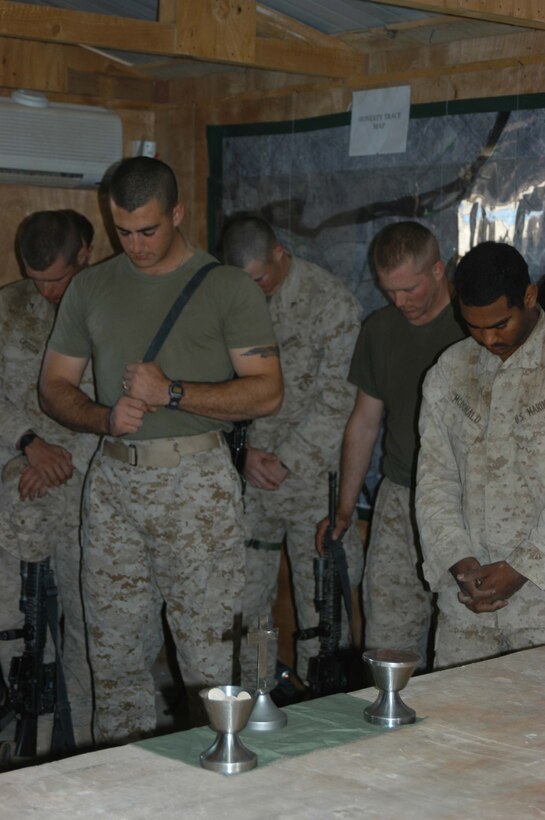 AR RAMADI, Iraq (March 27, 2005) - Marines with Company B, 1st Battalion, 5th Marine Regiment, bow their heads in prayer while Navy Lt. Aaron T. Miller, the infantry battalion's chaplain, conducts Easter service at Camp Junction City here. The 32-year-old man of God from Redlands, Calif., visited Marines from the infantry battalion's five companies of whom he preached a hasty Easter service and served Holy Communion to. The effort, which lasted more than six hours, required Miller to travel to seven different places in the city where Marines are serving. Photo by Cpl. Tom Sloan