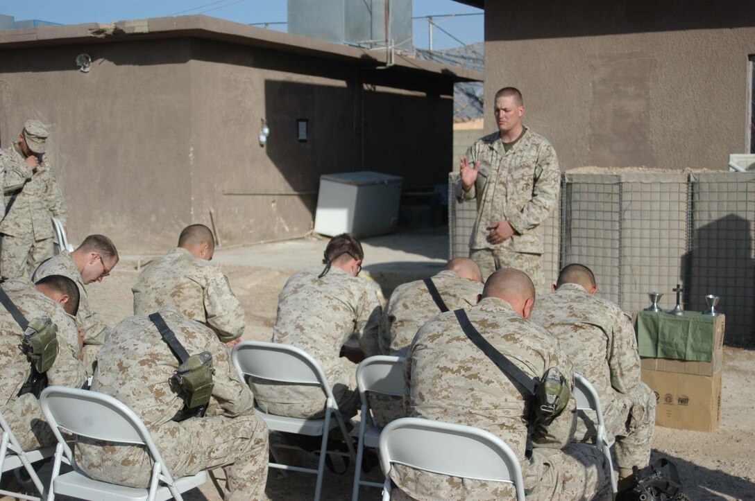 AR RAMADI, Iraq (March 27, 2005) - Marines with Company C, 1st Battalion, 5th Marine Regiment, bow their heads in prayer as Navy Lt. Aaron T. Miller, the infantry battalion's chaplain, conducts Easter service at Camp Snake Pit here. The 32-year-old man of God from Redlands, Calif., visited Marines from the infantry battalion's five companies of whom he preached a hasty Easter service and served Holy Communion to. The effort, which lasted more than six hours, required Miller to travel to seven different places in the city where Marines are serving. Photo by Cpl. Tom Sloan