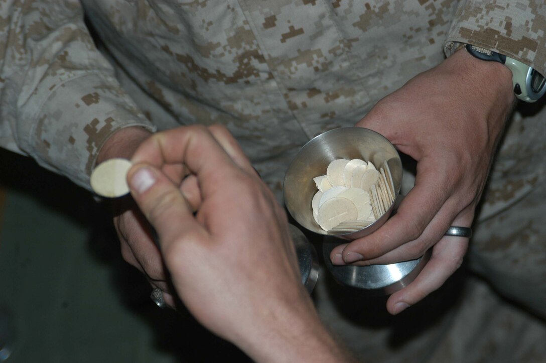 AR RAMADI, Iraq (March 27, 2005) - Nineteen-year-old Pfc. Rick R. Blakely, a rifleman with 3rd Squad, 4th Platoon, Company A, 1st Battalion, 5th Marine Regiment, takes Holly Communion from Navy Lt. Aaron T. Miller, the infantry battalion's chaplain, at the Government Center building here Easter Sunday. The 32-year-old man of God from Redlands, Calif., conducted a hasty, 15-minute Easter service for Blakely and other Company A Marines. Though the Easter celebration wasn't the same as Blakely is used to back home in Prescott, Mich., the 2004 Whittemore High School graduate said it would be one of his most memorable. Photo by Cpl. Tom Sloan